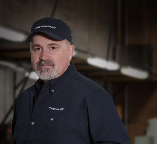 Thermal employee wearing uniform with embroidered logos on baseball cap and button up work shirt.